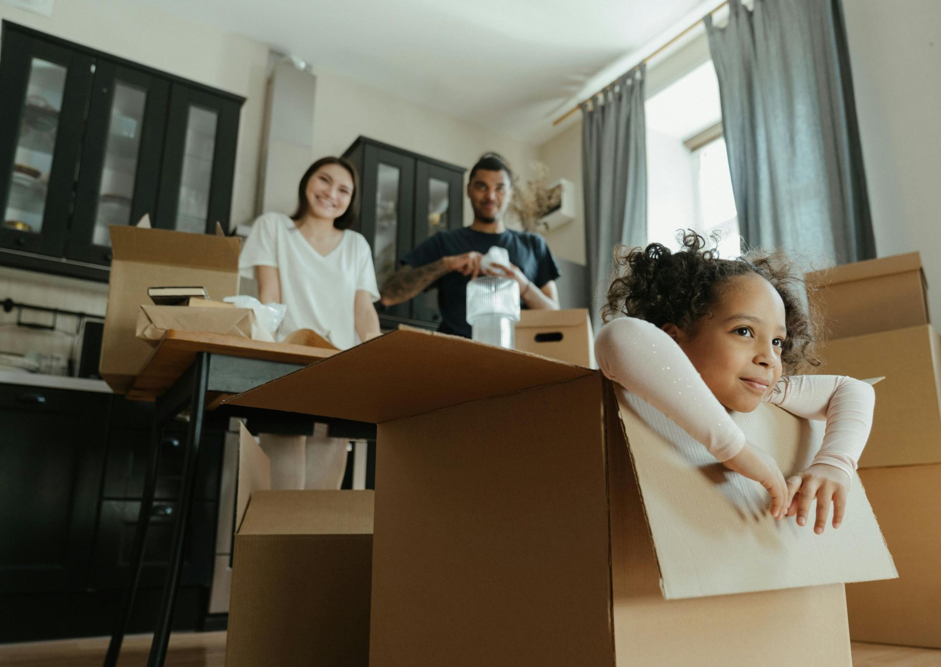 Family enjoys a joyful moment while unpacking boxes in their new kitchen.